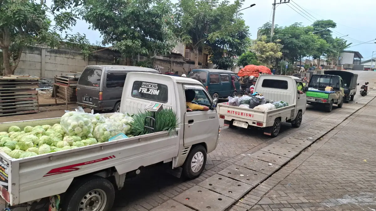 PASOKAN MELIMPAH: Antrean mobil pikap bermuatan sayuran dari petani berjejer di area Pasar Induk Among Tani Kota Batu. Liburnya program MBG pekan ini membuat pasokan sayur di pasar menumpuk.