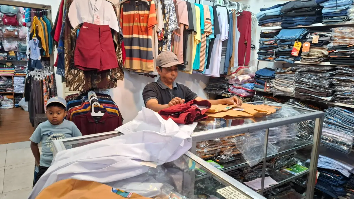 BERBURU SERAGAM SEKOLAH:  Salah seroang pembeli tampak memastikan ukiran seragam yang akan dibeli sesuai dengan kebutuhan.