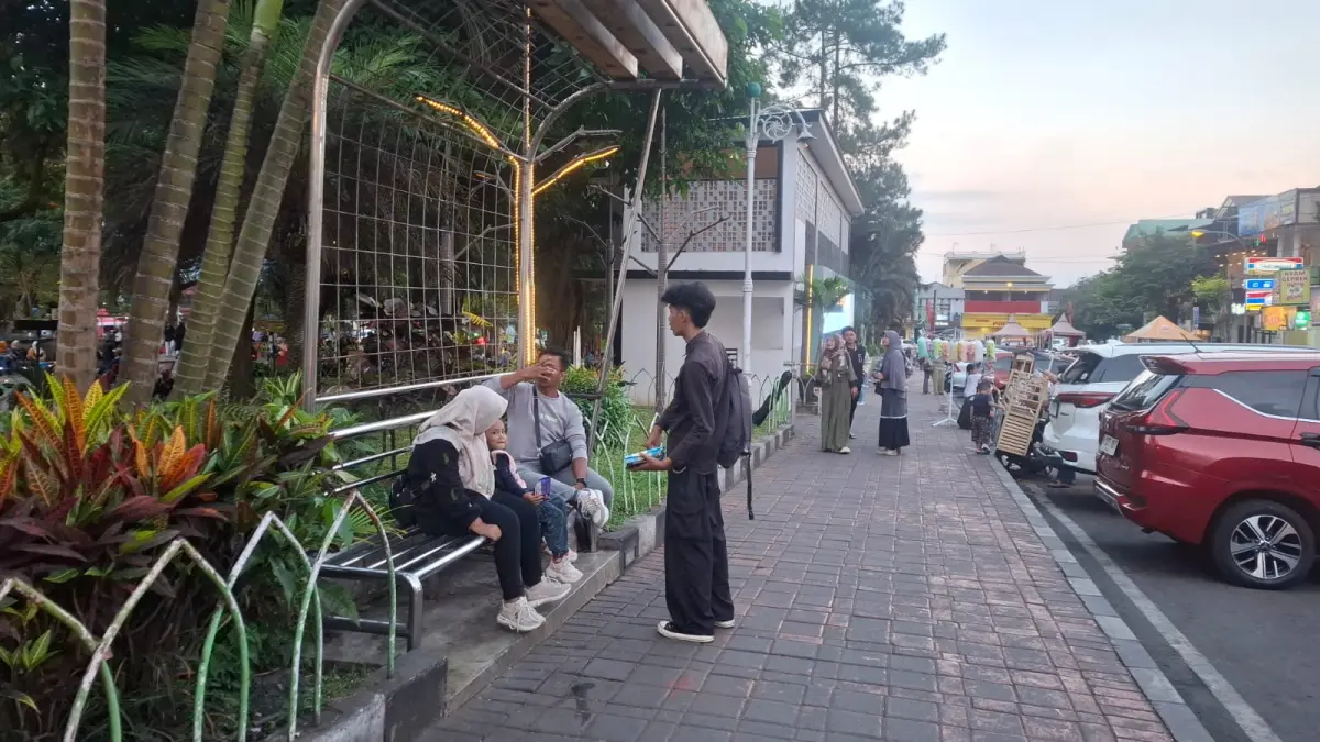 MODUS DONASI: Salah seorang pedagang jajanan bermodus aksi sosial tengah mempromosikan produknya ke beberapa pengunjung Alun-Alun Kota Batu pada Kamis lalu (2/7).