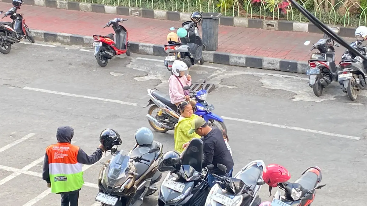 DITARIK PARKIR: Salah seorang jukir menarik biaya parkir kepada wisatawan di Alun-Alun Kota Wisata Batu pada Senin lalu (6/7).
