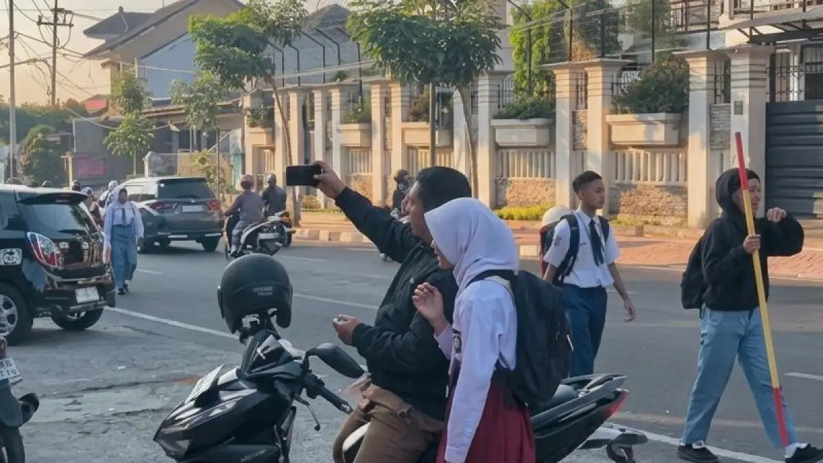 HARI PERTAMA SEKOLAH: Salah satu siswa tampak diantar oleh sang ayah ke sekolah untuk mengikuti kegiatan MPLS hari pertama di SMP Negeri 2 Batu kemarin (13/7).
