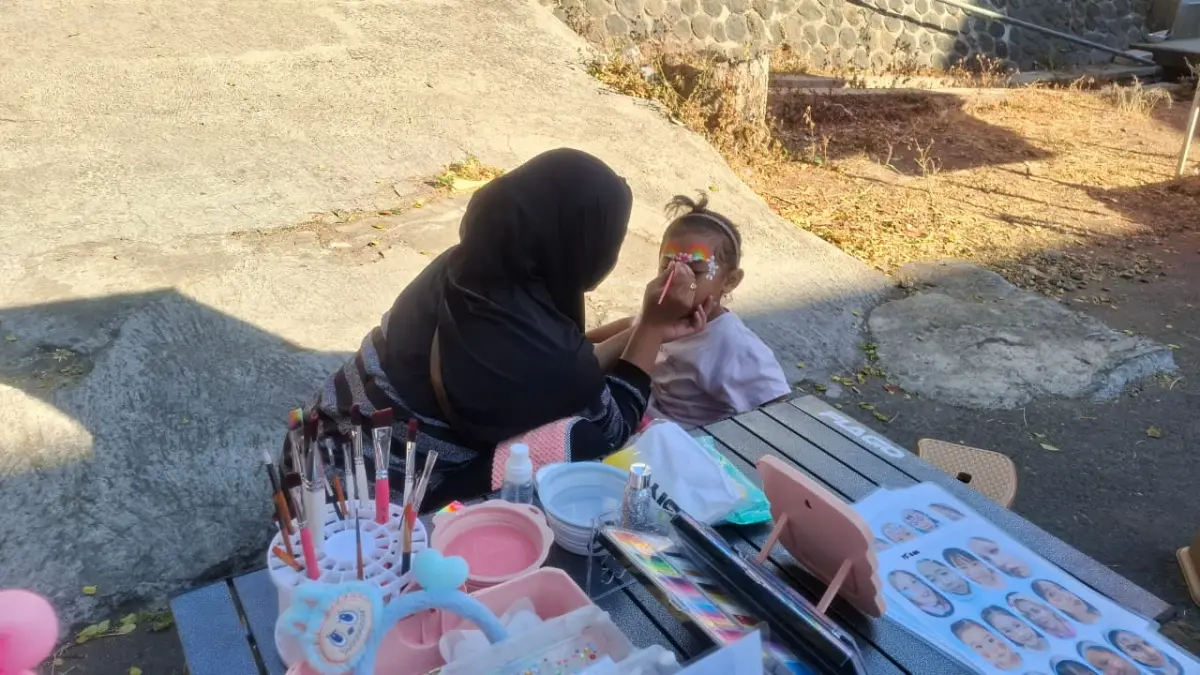 SENI MELUKIS WAJAH: Pemilik lapak face painting di CFD Mbatu Sae Kota Batu melayani permintaan lukis wajah salah seorang anak di area Stadion Gelora Brantas kemarin (26/7). (RAMIZARD RAFSANJANI/RADAR BATU)