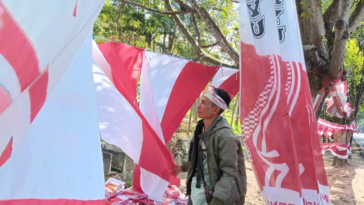 TUNGGU PEMBELI: Penjual atribut kemerdekaan di Jalan Indragiri, Pesanggrahan, Kecamatan Batu menunjukkan sejumlah model bendera kemarin (11/8). (INDAH MEI YUNITA/RADAR BATU)