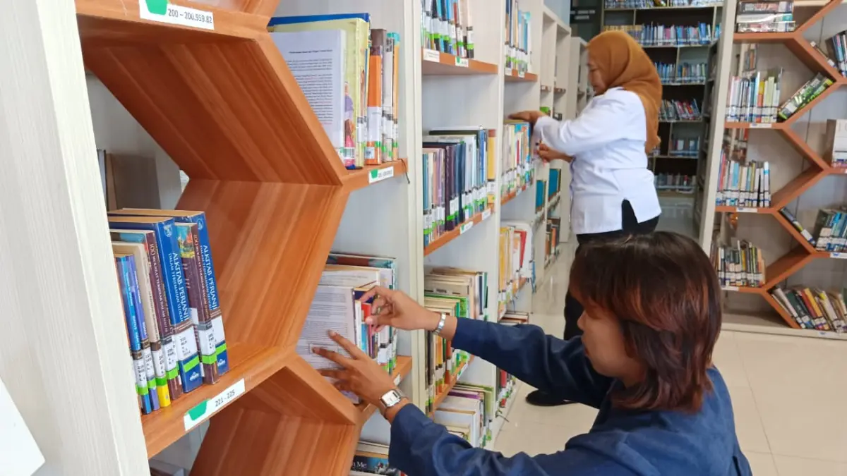 KELOLA KOLEKSI: Petugas Perpustakaan Daerah (Perpusda) Kota Batu menata koleksi buku beberapa waktu lalu. (INDAH MEI YUNITA/RADAR BATU)