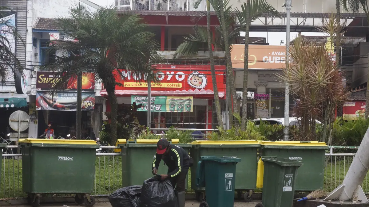GARDA TERDEPAN: Salah seorang tenaga kebersihan memilah sampah di Alun-Alun Kota Wisata Batu kemarin (31/8). (RORI DINANDA BESTARI/RADAR BATU)