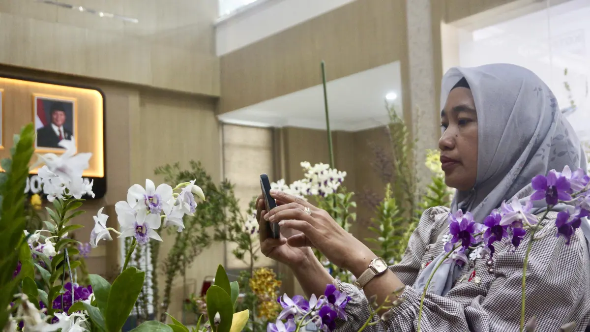 Salah seorang pengunjung memotret anggrek jenis Nong Alsagoff di Graha Pancasila pada Rabu (9/9). (Rori Dinanda Bestari/Radar Batu)