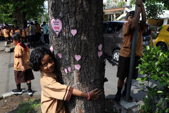RIANG: Anak SD di Kota Solo melakukan aksi memeluk pohon untuk menumbuhkan rasa cinta pada lingkungan.