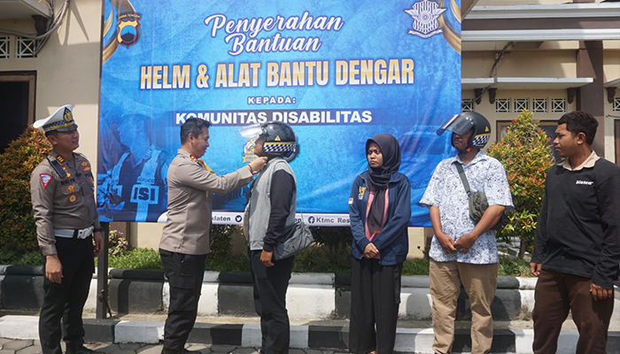 BERBAGI SENYUM: Kapolres Klaten AKBP Warsono menyerahkan helm berstiker khusus dan bantuan alat bantu dengar di halaman di Mapolres Klaten, Kamis (30/11)