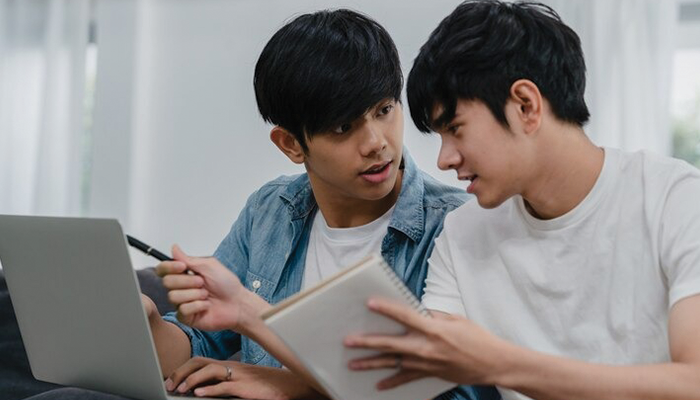 2 orang yang sedang berdiskusi sambil bermain laptop