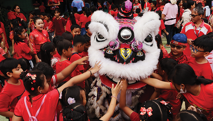 ATRAKTIF: Atraksi barongsai di halaman SD Warga disambut antusias siswa sekolah setempat kemarin. Siswa memberikan angpo ke mulut barongsai.
