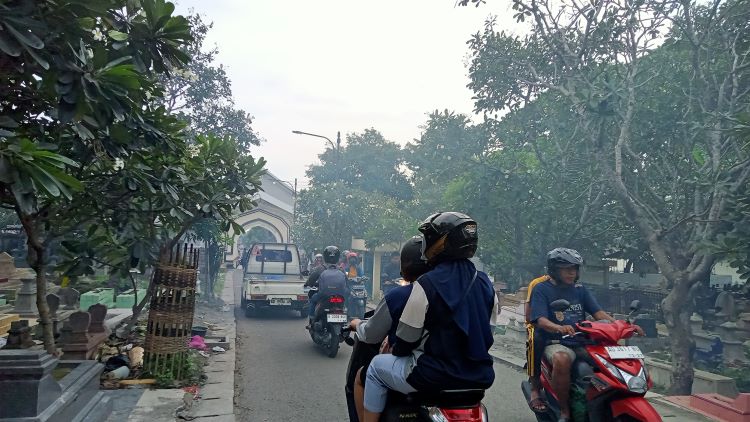 Para pengendara melalui jalan di tengah TPU Bonoloyo  Solo sebagai dampak penutupan Simpang Joglo (DOK. PRIBADI/ ELLEN FAHIRA AS SYAHRA)