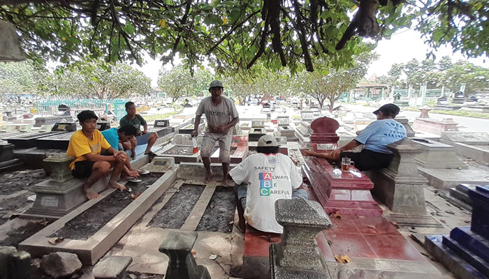 Sejumlah warga pembersih makam menunggu peziarah.