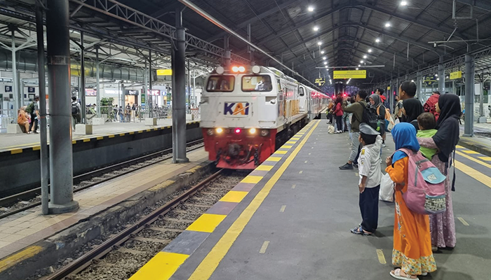 Penumpang berjajar menunggu keberangkatan kereta api.