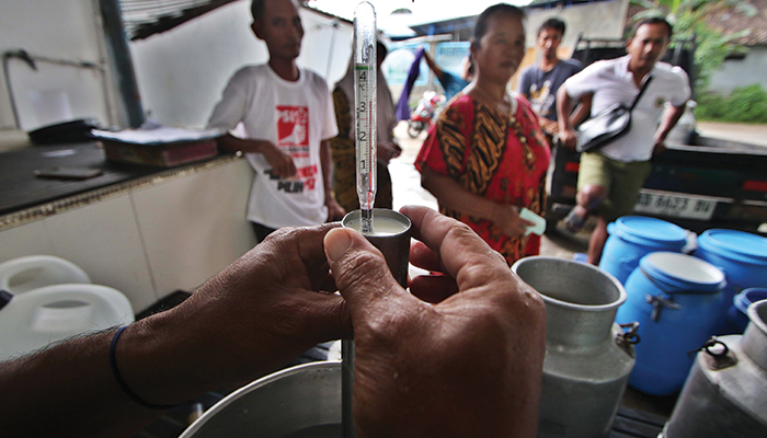 JAGA KUALITAS: Pekerja mengecek suhu susu sebelum dikirim ke berbagai daerah.