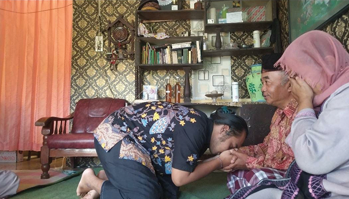 Anak sedang melakukan sungkeman lebaran kepada orang tua.