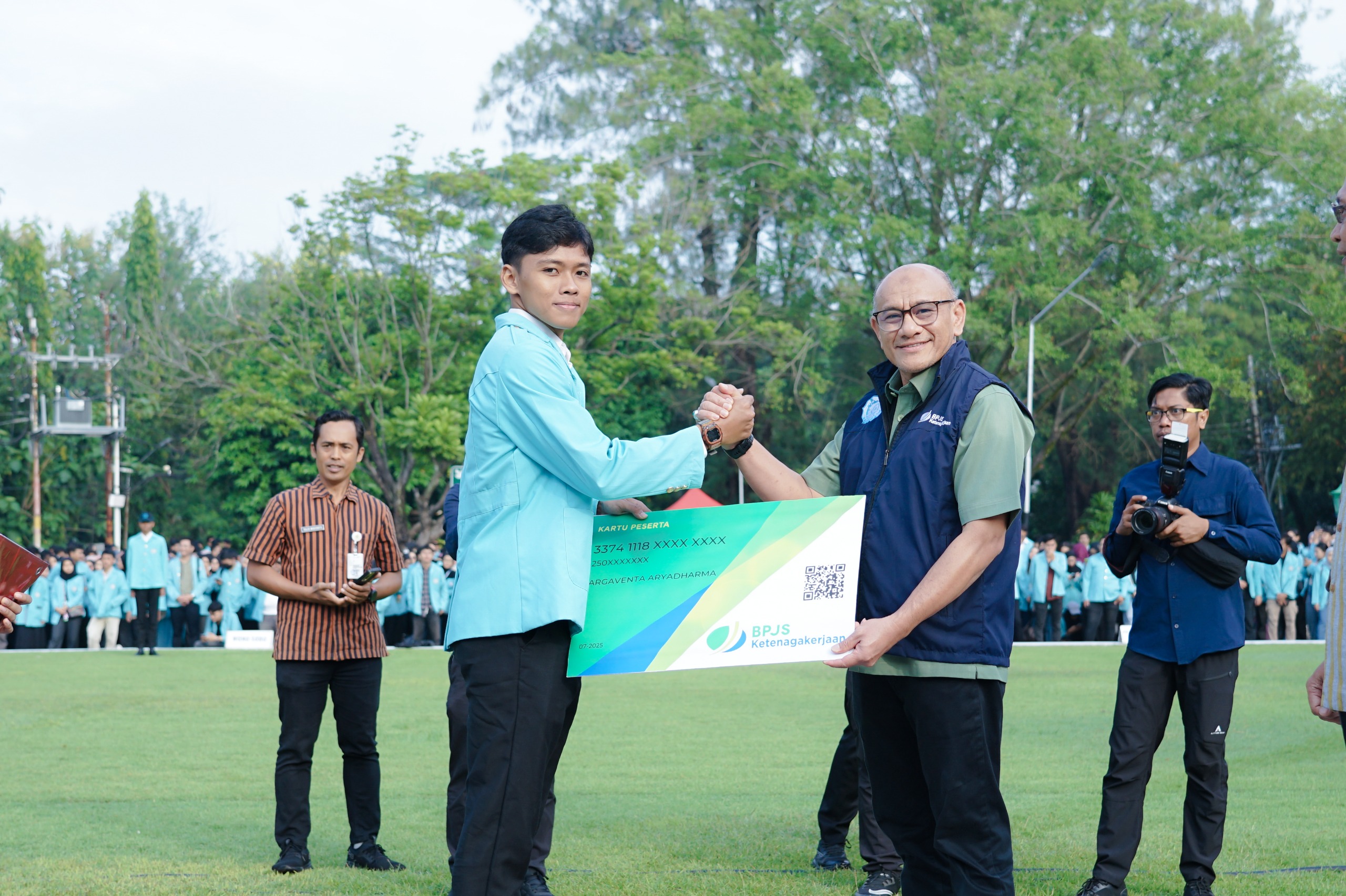 Simbolis Deputi Bidang Learning and Development BPJS Ketenagakerjaan, Suwilwan Rachmat menyerahkan kartu BPJS Ketenagakerjaan ke mahasiswa UNS peserta KKN periode Juli-Agustus 2025.