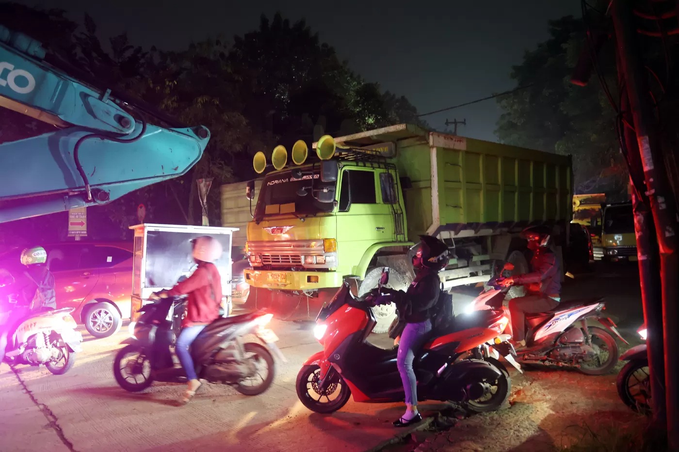 Ilustrasi Pengguna sepeda motor melintasi jalur yang di lewati truk tambang di Parung Panjang, Bogor, Jawa Barat.