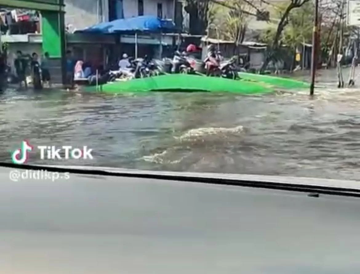 Seorang pengendara mobil nekat menerobos genangan banjir yang cukup tinggi dan diiringi dengan suara yang mirip dengan panduan navigasi Google Maps di Jalan Pantura Sayung, Demak.