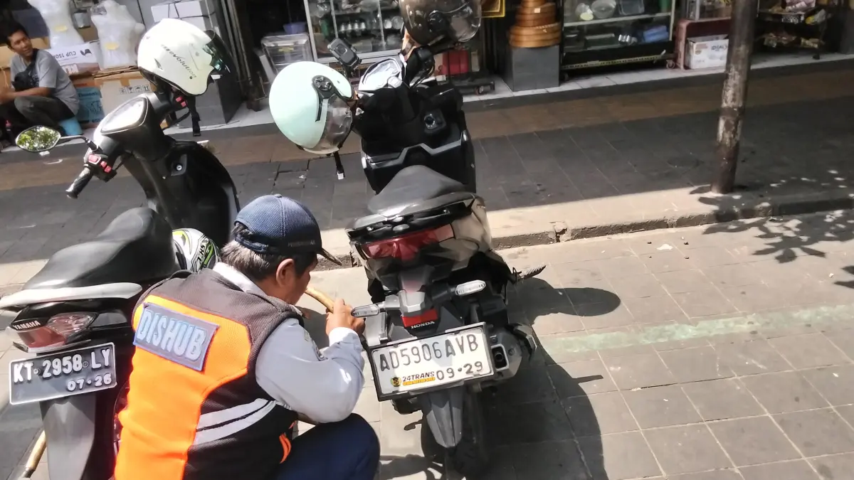 TEGAS: Petugas Dishub Kota Solo mengembok sepeda motor yang parkir sembarangan di kawasan Pasar Gede Solo. (ANTONIUS CHRISTIAN/SOLOBALAPAN.COM)