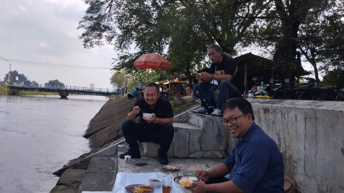 Pengunjung menikmati suasana teduh di bawah pohon trembesi di tepi Saluran Induk Colo Timur, Begajah, Sukoharjo. (Iwan Kawul/solobalapan.com)