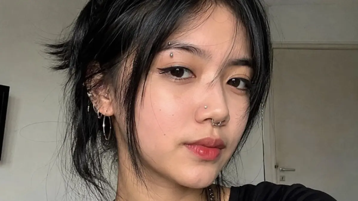 Ilustrasi seorang cewek mengenakan banyak piercing di hidung dan telinga. (AI GENERATED)