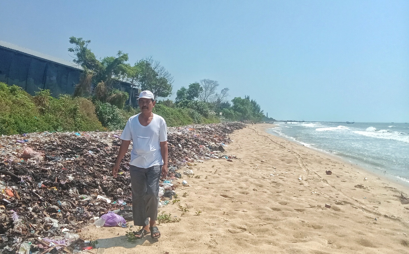 MENUMPUK: Warga berjalan di sekitar gundukan sampah yang ada di Pantai Desa Plawangan, Kecamatan Kragan baru-baru ini.