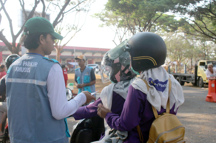 RESMI: Petugas parkir khusus yang bekerja sama dengan Dinas Perhubungan Jepara memberikan karcis parkir resmi kepada masyarakat yang ingin masuk ke arena Porprov di GBK Jepara kemarin.