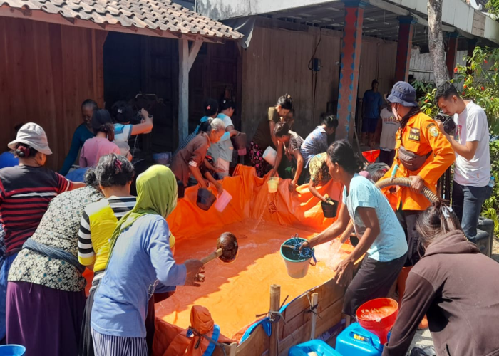 IMBAS KEKERINGAN: Warga mengambil air yang baru saja didistribusikan BPBD Grobogan.