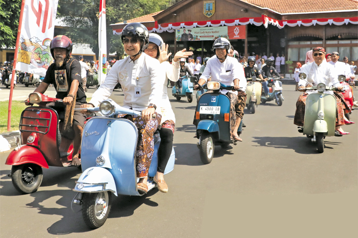 PURNA TUGAS: Mantan Bupati Kudus Hartopo (depan) bersama istrinya, Mawar Hartopo naik vespa untuk pulang dari pendapa ke rumahnya di Perumahan Muria Indah, Desa Gondangmanis, Bae, Kudus, kemarin.