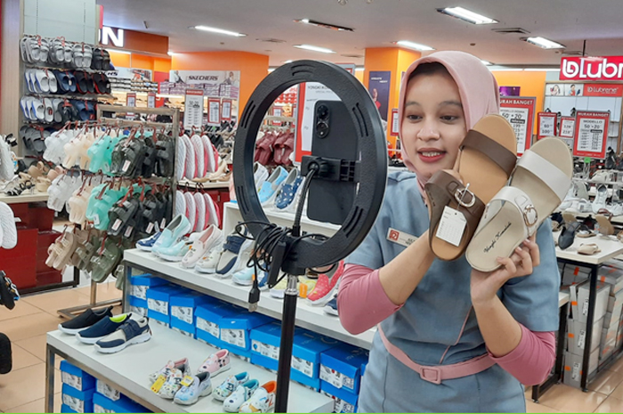LAGI NGE-LIVE: Host jualan online mereview sandal dan sepatu dari berbagai brand di depan kamera di Ramayana Store Kudus.