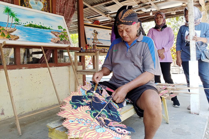 SEMANGAT: Lasmono, perajin wayang kulit di Desa Purwosari, Blora, saat menunjukkan hasil kreasinya.