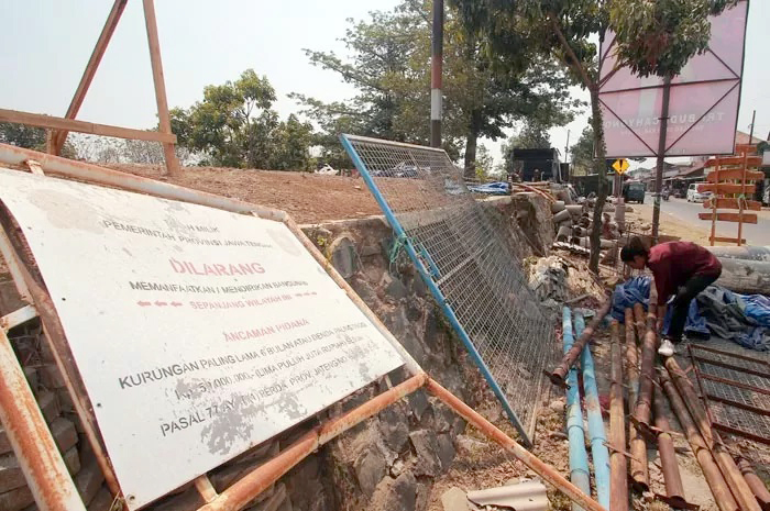 MULAI DIBONGKAR: Masyarakat menata komponen sisa bangunan yang sempat berdiri di atas tanggul aliran SWD 2 untuk dipindah ke tempat lain.