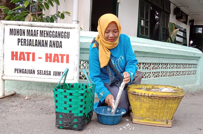 JUALAN: Sunarti, pedagang jajan gethuk sedang memarut kelapa di sekitar Pondok Raudhatut Thalibin, Leteh, Rembang, Senin (13/11).