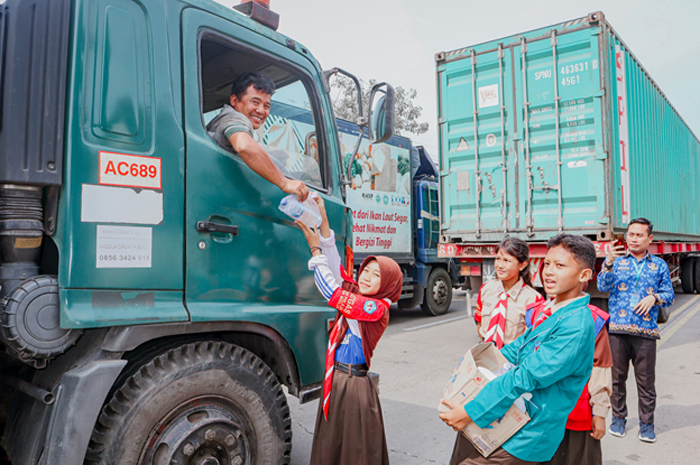 TURUN KE JALAN: Anak didik SMPN 3 Rembang turun ke jalan membagikan nasi bungkus kepada para sopir yang terjebak macet di Jalan Pantura Rembang kemarin.