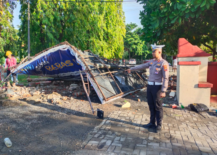 OLAH TKP: Petugas kepolisian menunjukkan kondisi reklame dan pagar kantor Bupati Rembang yang hancur usai ditabrak truk pada Senin (11/12).