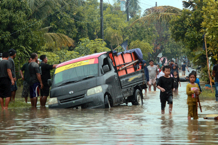 PENCEGAHAN: Sebuah mobil terperosok ke selokan saat banjir di Desa Clering Selasa (23/1) lalu. Kemarin, BPBD Jepara mulai menutup tanggul yang jebol agar tidak terjadi banjir susulan.