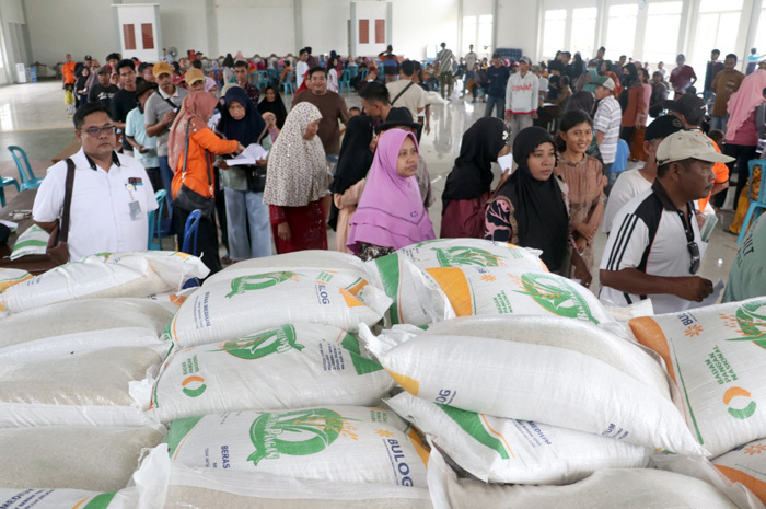 AMBIL BERAS: Warga Desa Kandangmas, Kecamatan Dawe antre untuk mendapatkan bantuan beras di gedung Serbaguna Kandangmas kemarin.