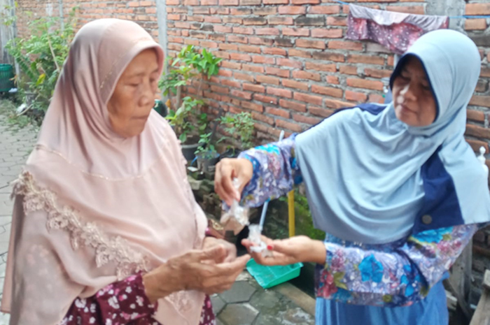 BERANTAS JENTIK NYAMUK: Kader Gerbastik Puskesmas Jati menabur bubuk abate di tempat penampungan air.