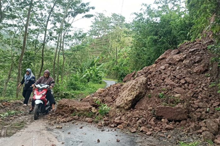 TERTUTUP: Pengendara motor mencoba melewati material longsor yang menutup akses utama ke Desa Blingoh, Donorojo, kemarin.