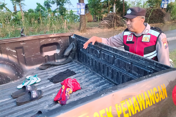 BARANG BUKTI: Anggota Polsek Penawangan menunjukkan baju dan sandal dari anak yang tenggelam di persawahan yang terendam banjir di Desa Penawangan, Kecamatan Penawangan, Grobogan, Kamis (8/2).