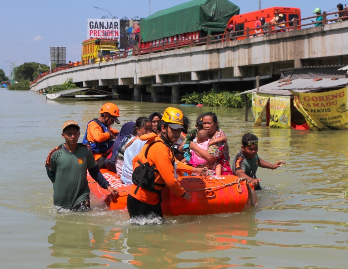 GERAK CEPAT: Relawan BPBD setempat mengevakuasi rombongan dari rumah yang terendam banjir di Desa Karanganyar. Di dalam rombongan tersebut ada ibu dan anak yang juga turut dievakuasi.