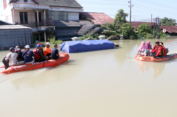 EVAKUASI WARGA: Petugas penaggulangan bencana mengevakua si korban banjir menggunakan perahu karet melintas Jalur Pantura Kudus-Demak.