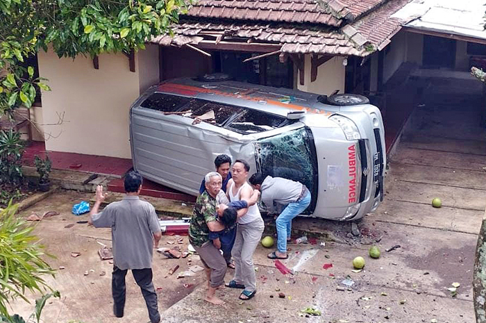TERJUN BEBAS: Warga mengevakuasi sopir ambulans pengangkut snak KPPS yang terguling di Desa Japan, Dawe, Kudus, Rabu (14/2).