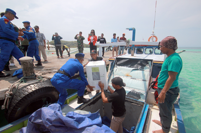 BERDEDIKASI: Petugas memindahkan logistik pemilu dari perahu untuk didistribusikan ke TPS saat tiba di dermaga Pulau Genting, Karimunjawa, Jepara, kemarin.