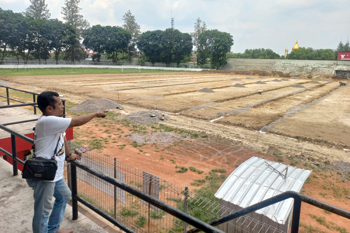 PANTAU: Ardi (baju putih) pengawas proyek Stadion Krida Bhakti Purwodadi sedang menunjukkan detail capaian pengerjaan, Selasa (5/3).