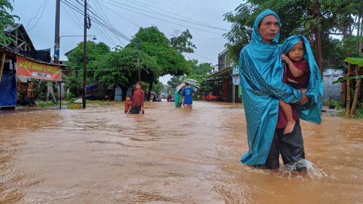 MENONTON: Seorang warga dari Sowan Lor, Kecamatan Kedung, Jepara membopong anaknya melihat keramaian akibat banjir.