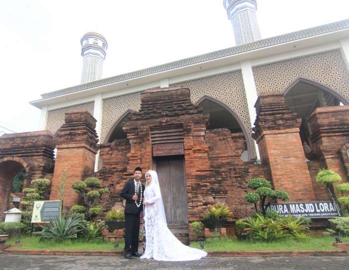 KIRAB MANTEN: Pasangan pengantin foto bersama di depan Gapura Paduraksa Masjid Wali Loram Kulon usai melaksanakan tradisi kirab manten.
