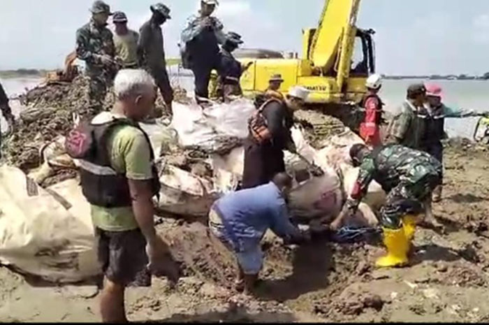 PROSES SELAMATAN: Warga menyembelih kambing kendit di atas tanggul jebol di Norowito, Demak.