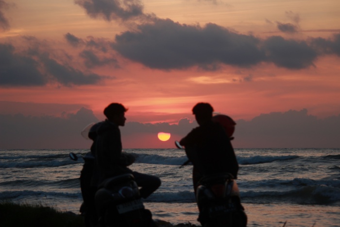 MENAWAN: Pengunjung bercengkerama di atas motornya sembari menikmati pemandangan matahari terbenam di Pantai Bandengan.