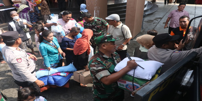 GEMBIRA: Para pengungsi pulang ke rumah dibantu anggota TNI dan Polri mengangkut barang ke dalam mobil kemarin.